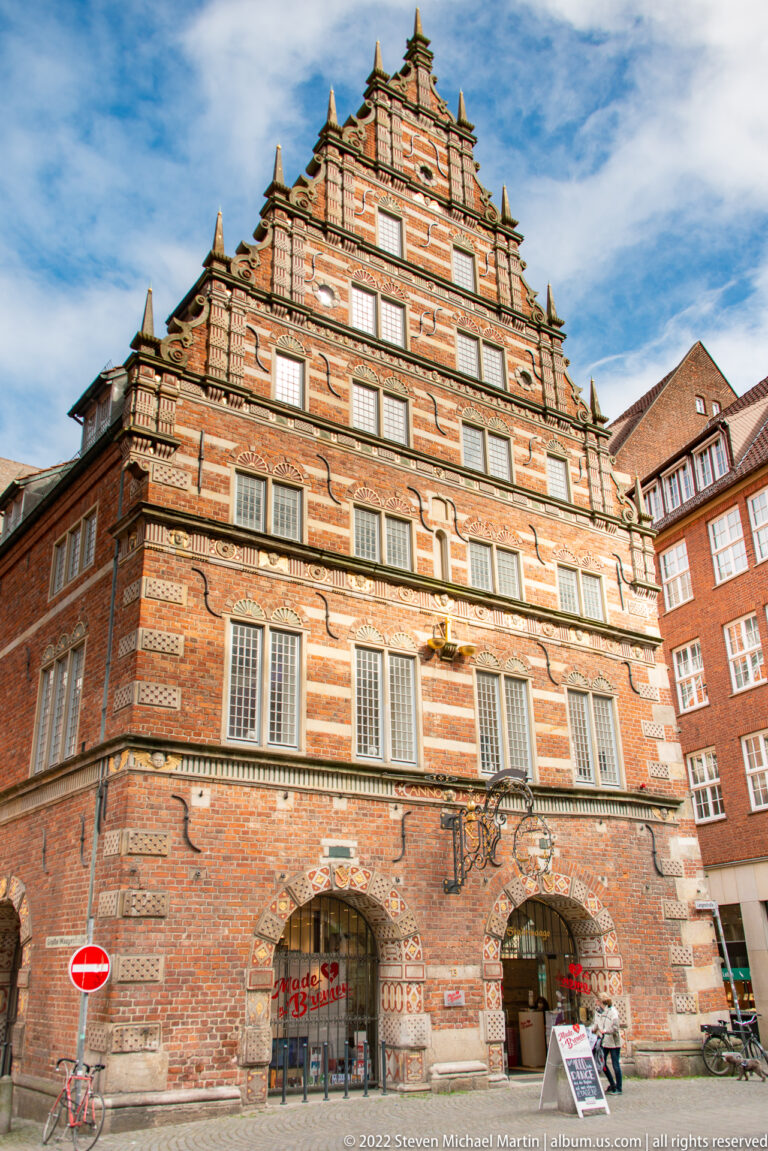 Historic Bremen Stadtwaage with stepped brick gable, pale horizontal bands, rows of windows, and arched ground-floor openings.
