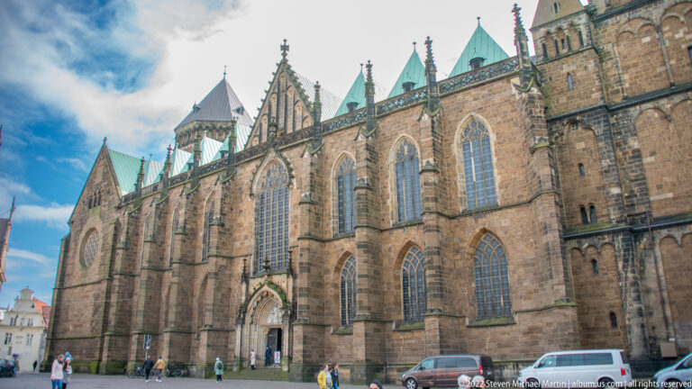 Long stone side façade of Bremen St. Peter’s Cathedral with pointed windows, buttresses, gables, and green-roofed towers.