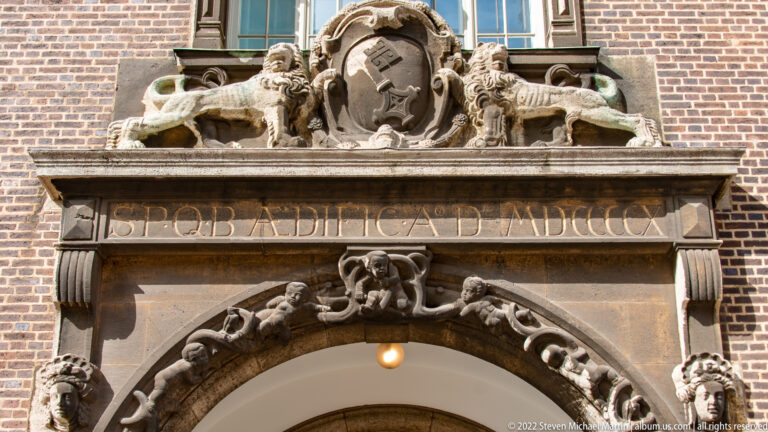 Ornate stone portal with Bremen key coat of arms, Latin inscription, sculpted figures, and carved masks.
