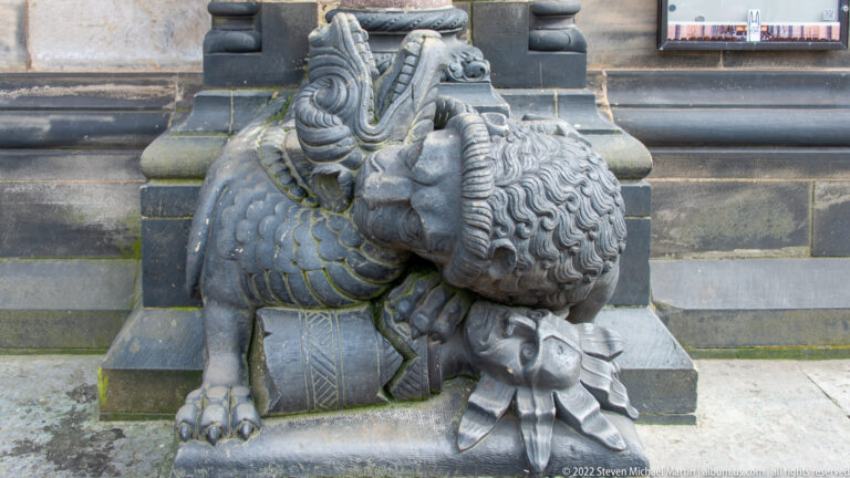 Large reclining carved beast with curled mane and heavy paws beside the entrance of Bremen Cathedral.
