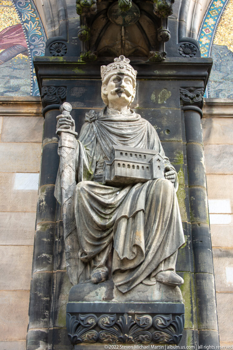 Crowned seated stone figure holding a staff or scepter in an exterior niche of Bremen Cathedral.