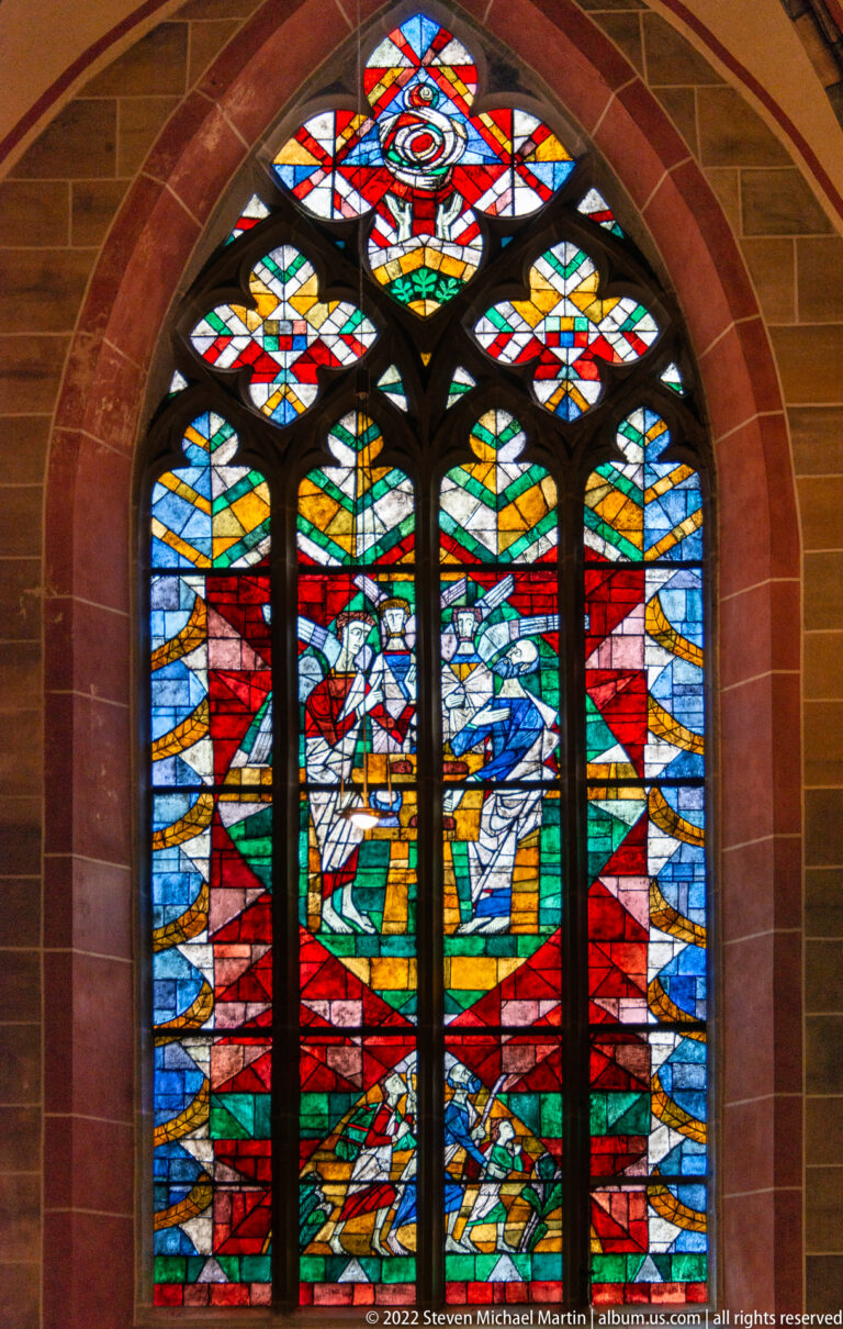 Large multicolored stained-glass window with figurative forms set within a pointed arched opening in Bremen Cathedral.