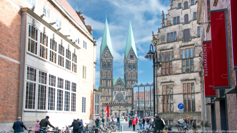 Pedestrian street and bicycles leading toward the twin green-roofed towers of Bremen St. Peter’s Cathedral.