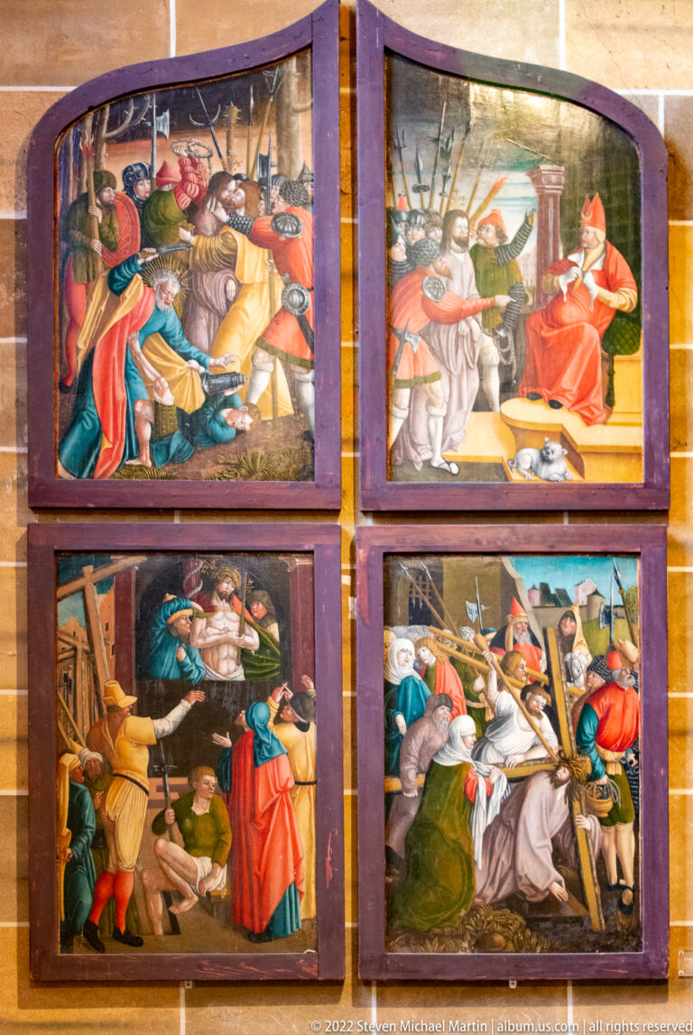Four framed religious narrative paintings arranged in a two-by-two grid on a wall.