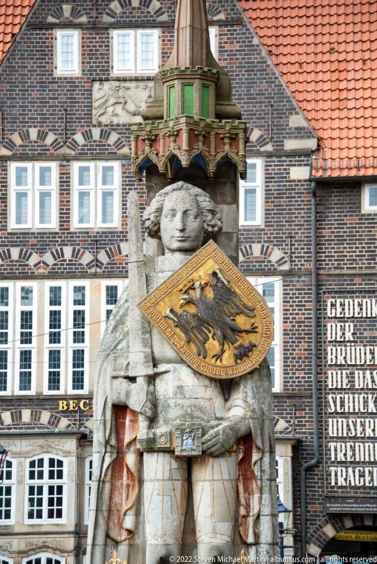Stone statue of Bremen Roland holding a shield with the imperial eagle beneath a decorative canopy.