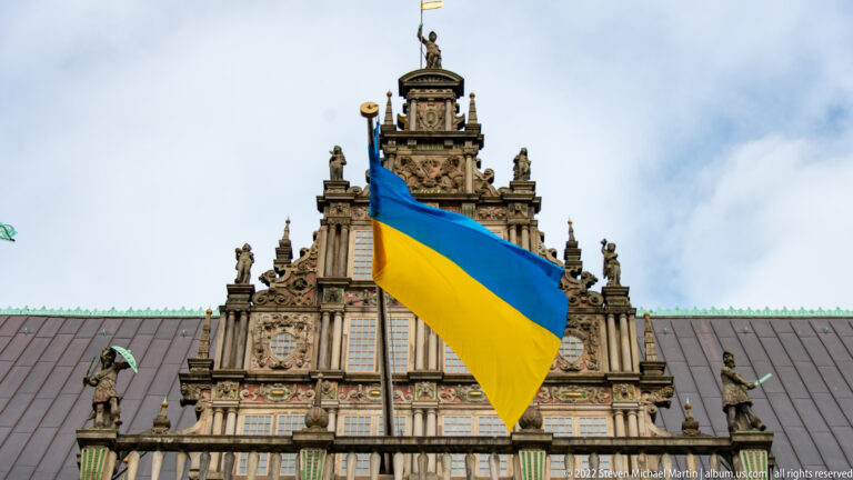 Close view of Bremen Town Hall’s central ornate gable with a large Ukrainian flag draped across it.