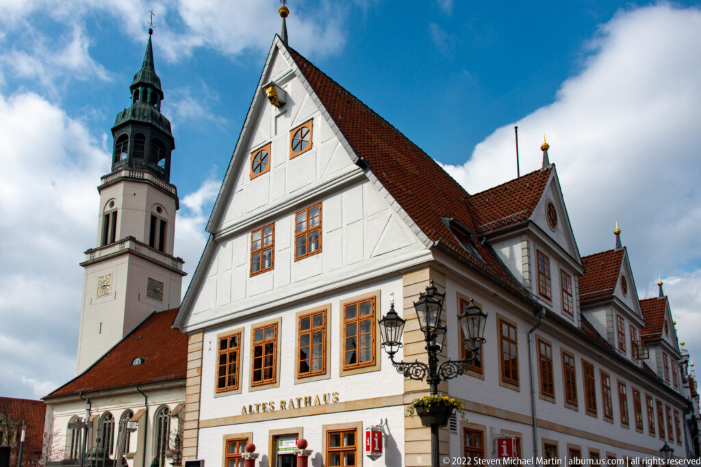 Gabled white Old Town Hall with ochre trim in front of the square tower of Stadtkirche St. Marien.