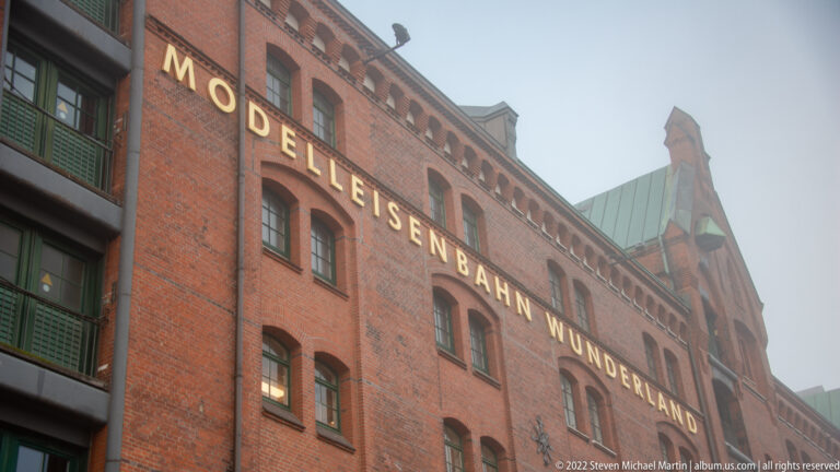 Red-brick warehouse façade with tall arched windows and large Modell Eisenbahn Wunderland lettering.