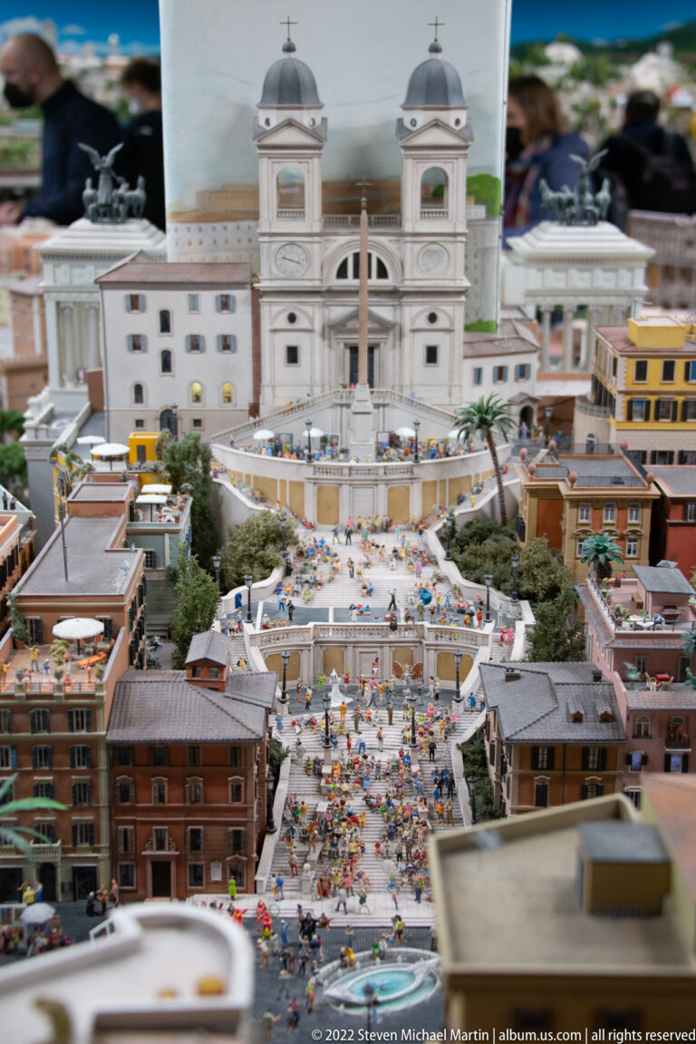 Miniature Spanish Steps crowded with figures, leading uphill to the twin-towered Trinità dei Monti church.