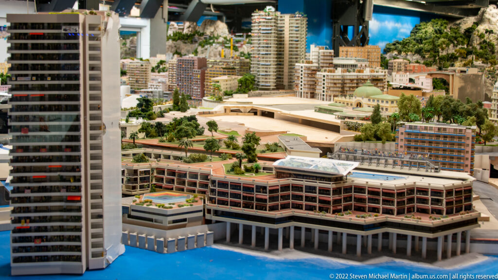 Miniature modern waterfront district with high-rise towers, terraced buildings, trees, and bright blue water.