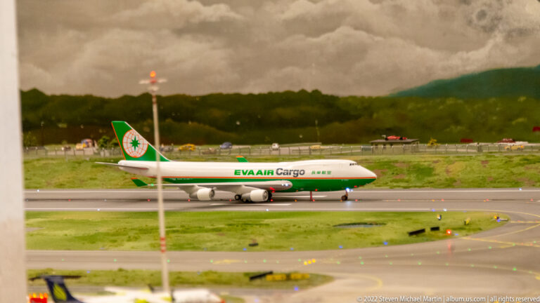 EVA Air Cargo Boeing 747 freighter model on the miniature airfield beneath a dark clouded backdrop.