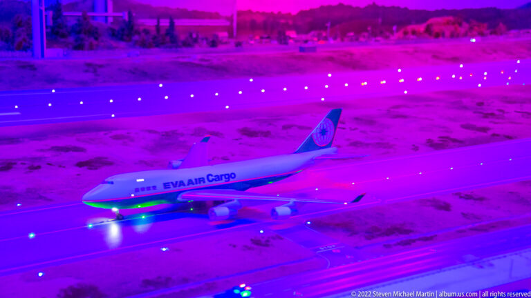 EVA Air Cargo Boeing 747 freighter model on a runway illuminated in vivid purple and blue light.