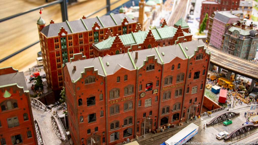 Red-brick Speicherstadt-style warehouse model with stepped gables, arched windows, green roofs, and nearby rail lines.