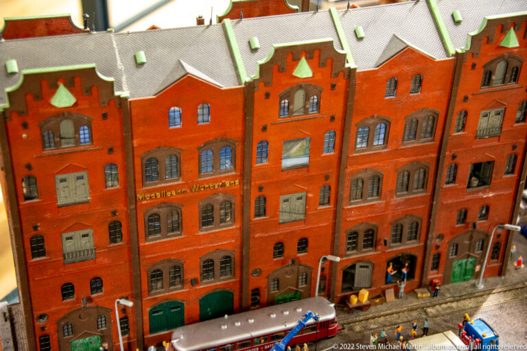 Red-brick Speicherstadt-style warehouse model with narrow gables, arched windows, green roof details, and ground-level activity.