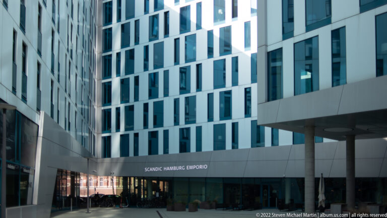 Scandic Hamburg Emporio entrance in a modern white courtyard with irregular dark windows and a projecting canopy.