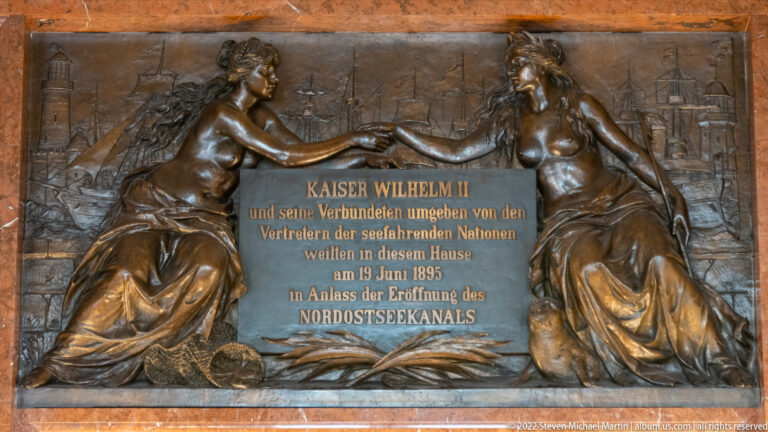 Bronze plaque with two seated female figures commemorating Kaiser Wilhelm II and the 1895 opening of the Nord-Ostsee-Kanal.