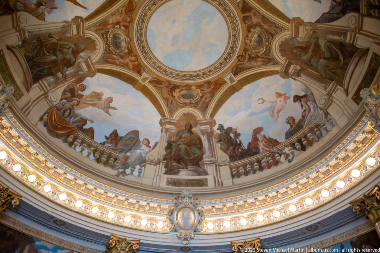 Painted Rathaus dome with allegorical figures above a balustrade-like ring, gilded cornice, medallions, and rows of lights.