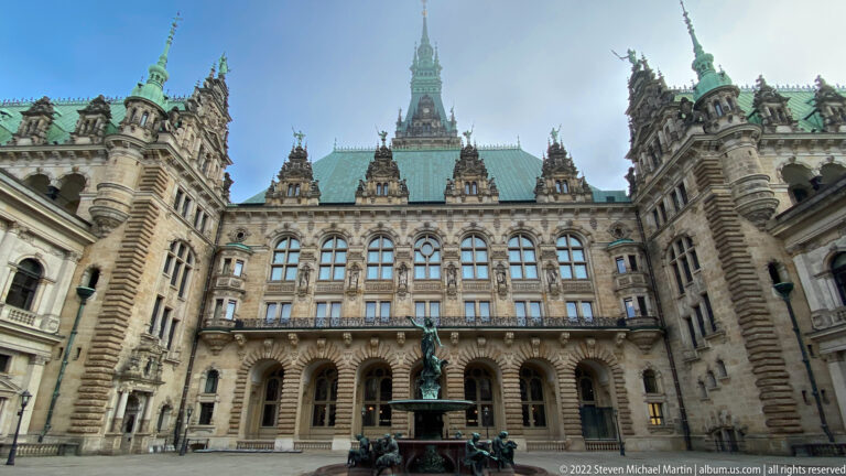 Hygieia Fountain centered in Hamburg Rathaus courtyard beneath ornate façades, gables, and green copper roofs.