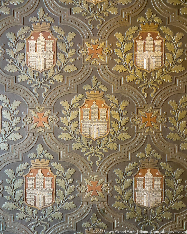 Repeating Hamburg coat-of-arms motifs surrounded by scrolling foliage and small stars on an ornate patterned surface.