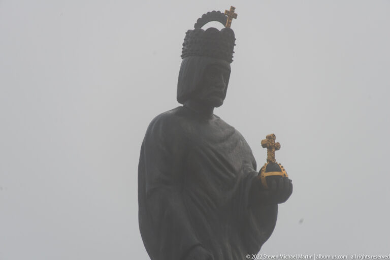 Close upward view of crowned Barbarossa statue holding a gilded imperial object against dense fog.