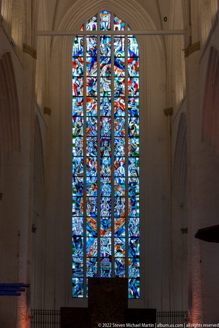 Tall multicolored stained-glass window framed by pale Gothic masonry at the end of St. Catherine’s Church nave.