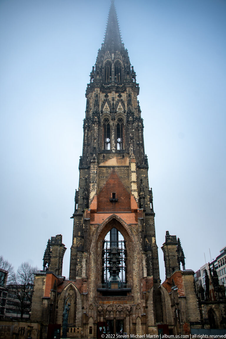 St. Nikolai Memorial tower rising from the roofless Gothic west front into a pale foggy sky.