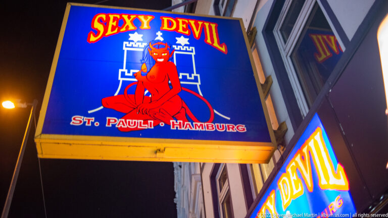 Neon “Sexy Devil” sign with red cartoon devil and the words “St. Pauli Hamburg” against the night sky.