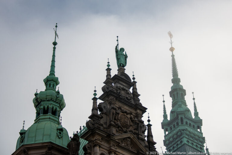 Ornate Hamburg Rathaus roofline with green copper towers and a darker central sculptural pavilion.