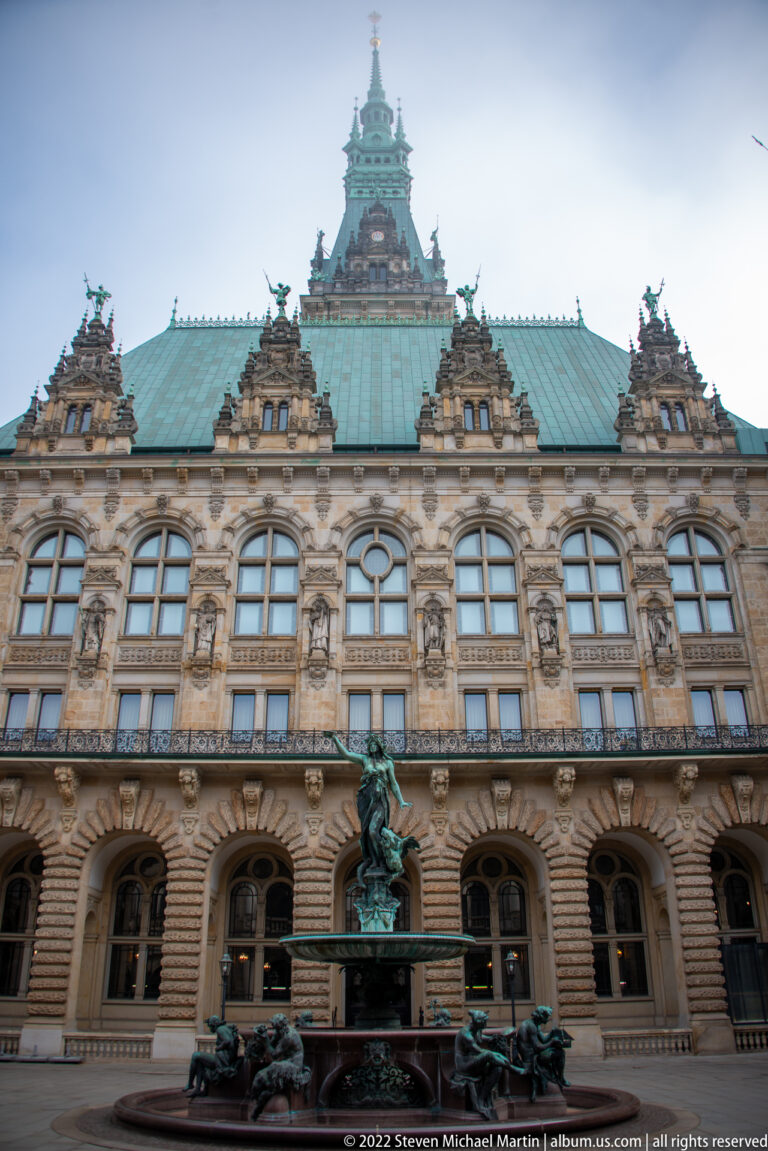 Hygieia Fountain centered before the ornate courtyard façade and green copper roof of Hamburg Rathaus.