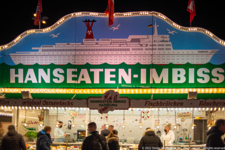 Hanseaten-Imbiss seafood stall with a large ship illustration, green lettering, and customers at the counter.