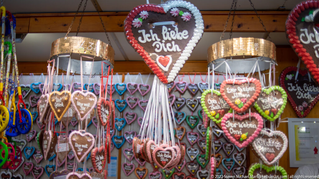 Rows of decorated gingerbread hearts hanging from ribbons, including a large heart reading Ich liebe Dich.