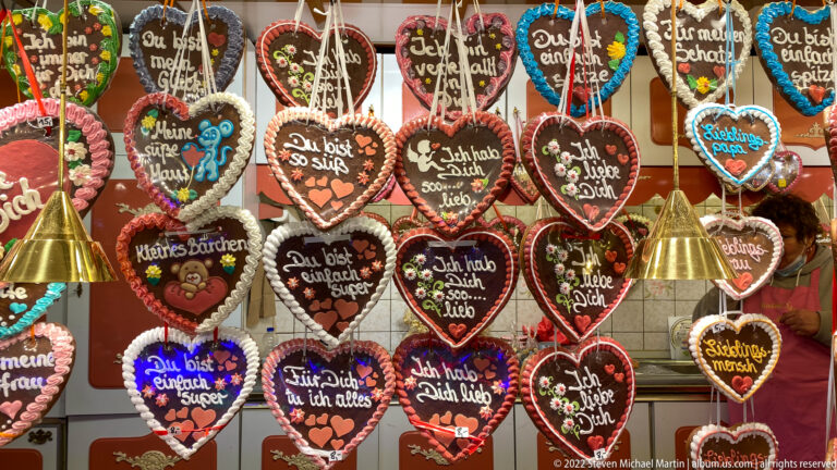 Rows of decorated gingerbread hearts with colorful icing, ribbons, flowers, and German affectionate inscriptions.