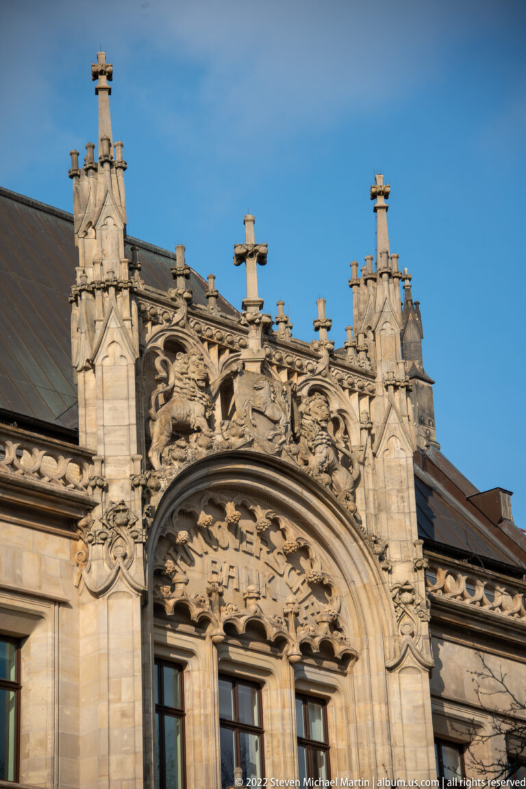 Carved stone pediment with scrollwork, heraldic motifs, finials, and the word ZEIT above a window.