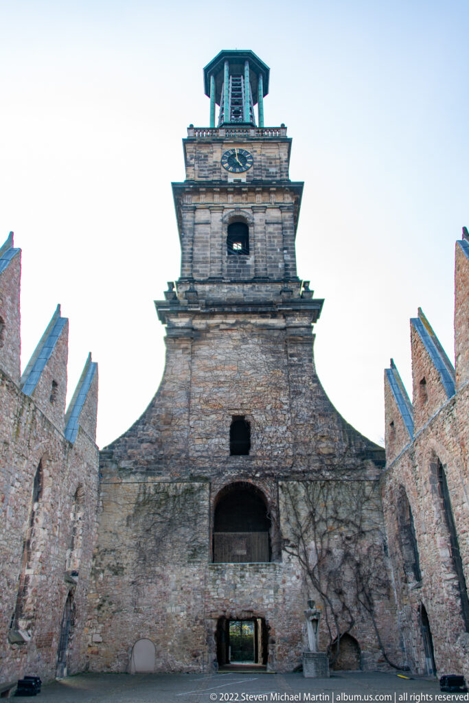 Damaged stone tower of Aegidienkirche rising between roofless church walls and empty window openings.