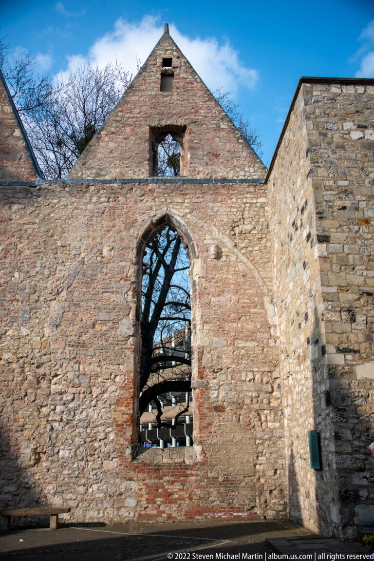 Brick gable of Aegidienkirche with a tall empty pointed-arch window and rough stone wall beside it.