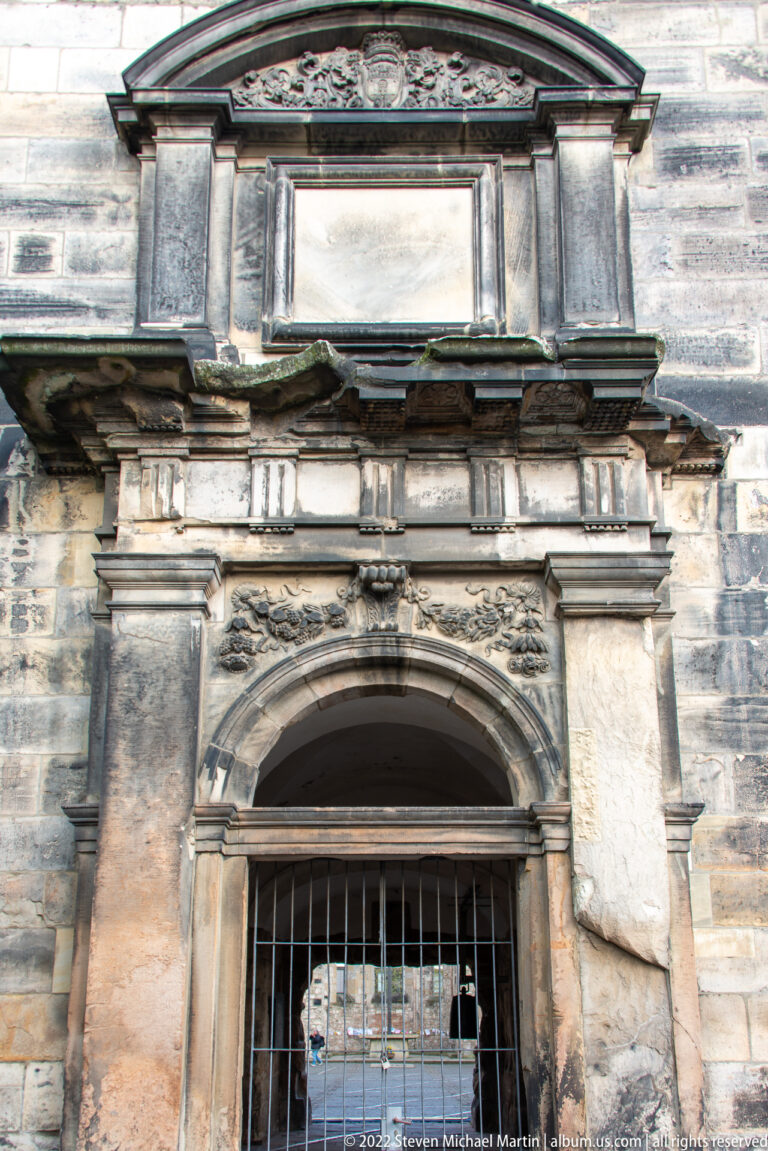 Weathered stone portal with pilasters, rounded arch, cornice, and triangular pediment at Aegidienkirche.