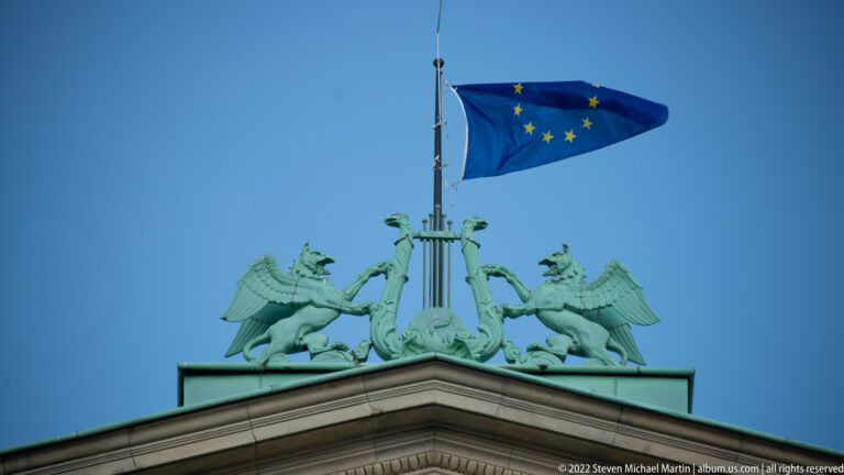 EU flag above a green-patinated roof crest with paired winged creatures on the Staatsoper Hannover.