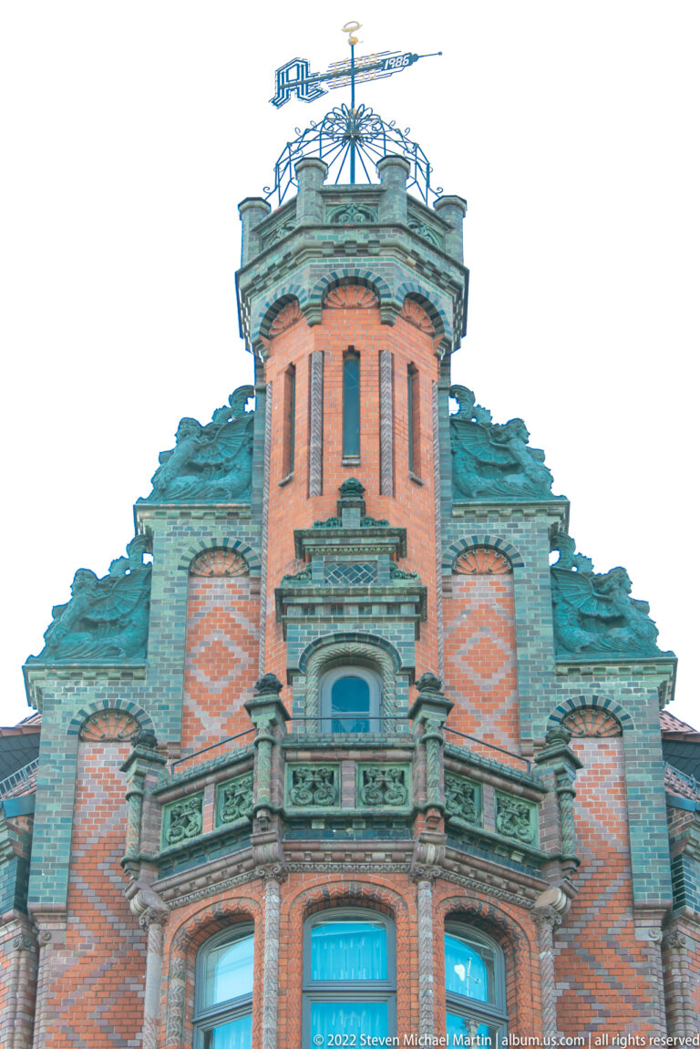 Polygonal brick roof turret with green-patinated metal details, ornate cresting, and a weather vane.