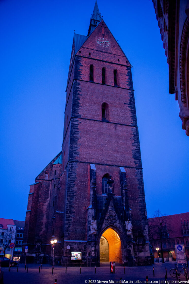 Massive brick Marktkirche tower at blue hour with a warmly illuminated entrance arch at street level.