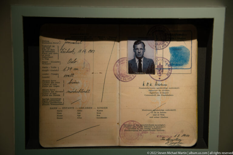 Open historic identification document with male portrait, handwritten entries, official stamps, and blue fingerprint or ink mark.