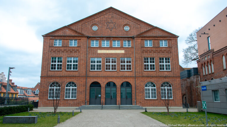 Symmetrical brick synagogue façade with Star of David in the gable, arched windows, and central entrance.