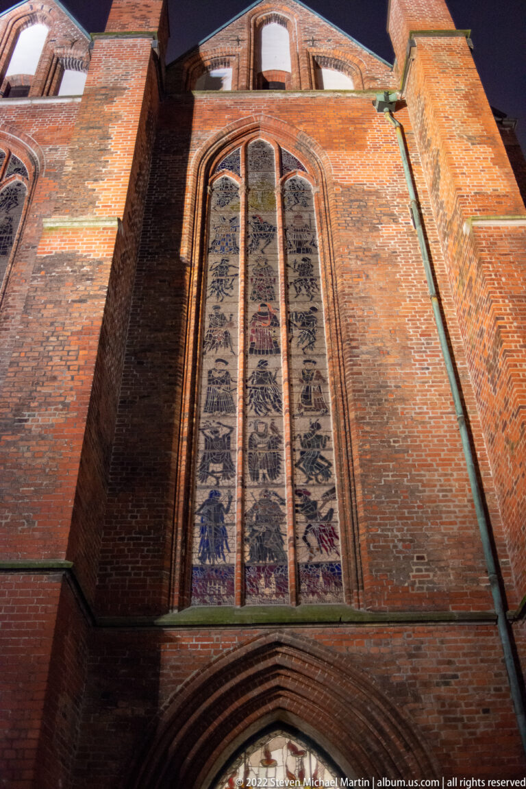Exterior view of Alfred Mahlau’s tall 1956/57 Dance of Death stained-glass windows in the north wall of St. Mary’s Church, Lübeck.