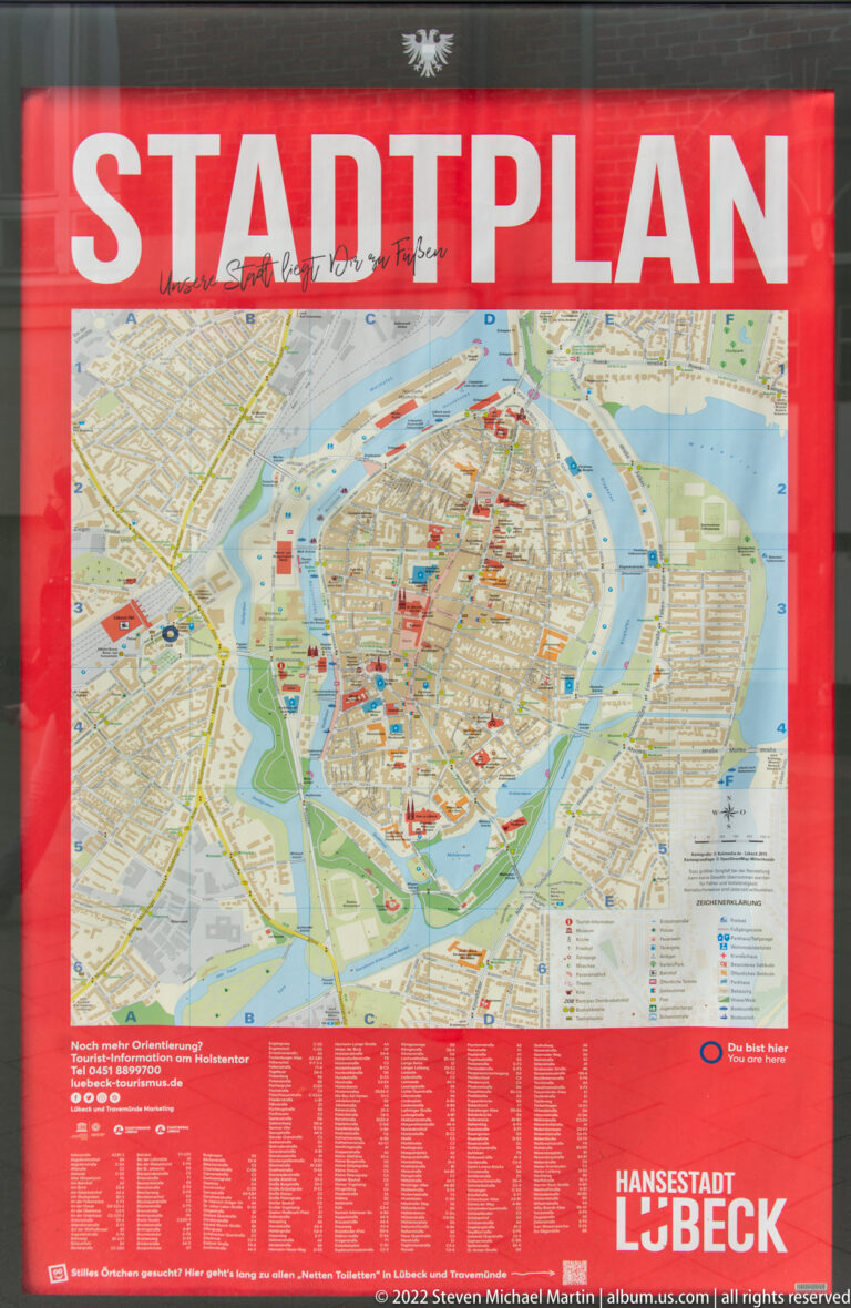 Public city map of Lübeck in a red frame, showing the historic center, surrounding waterways, streets, and landmarks.