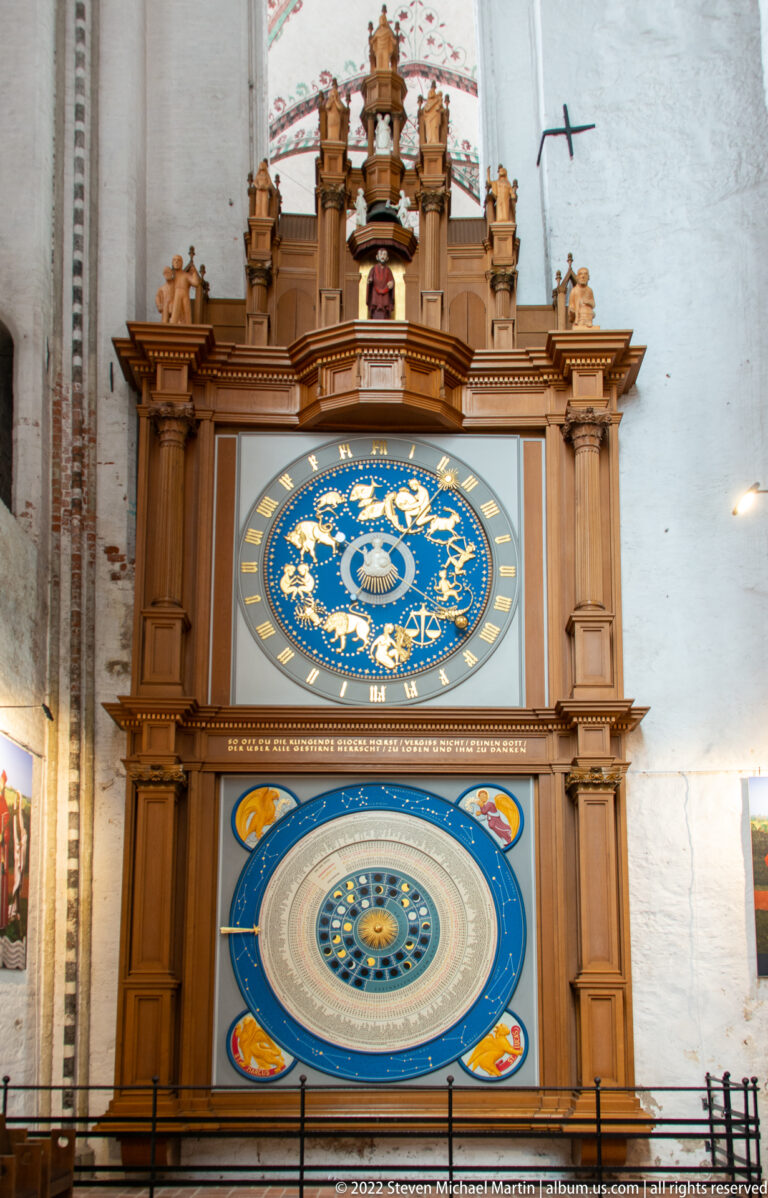 Full astronomical clock in a tall wooden case, with zodiac dial above a larger calendar and lunar dial.