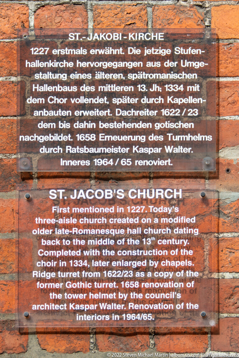 Bilingual plaque on brick identifying St. Jacob's Church and describing its medieval construction and later renovations.