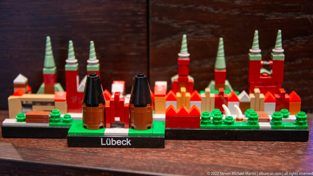 Colorful miniature labeled Lübeck with red buildings, green church spires, trees, and simplified towers.
