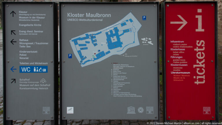 Visitor information panels for Kloster Maulbronn with UNESCO site map, directional signs, and ticket information.