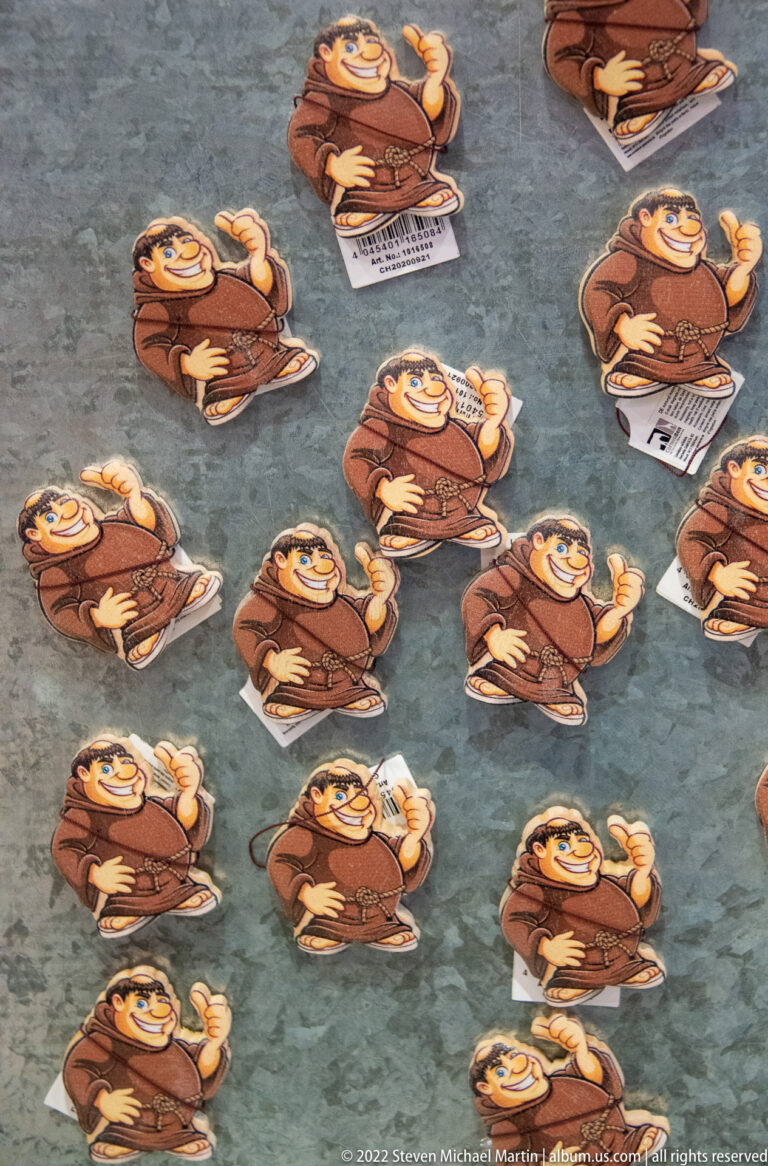 Rows of cartoon monk souvenir magnets scattered across a gray display surface.