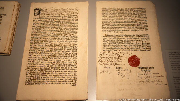 Open historic German document with dense printed text, handwritten notes, signatures, and a red seal on the right page.