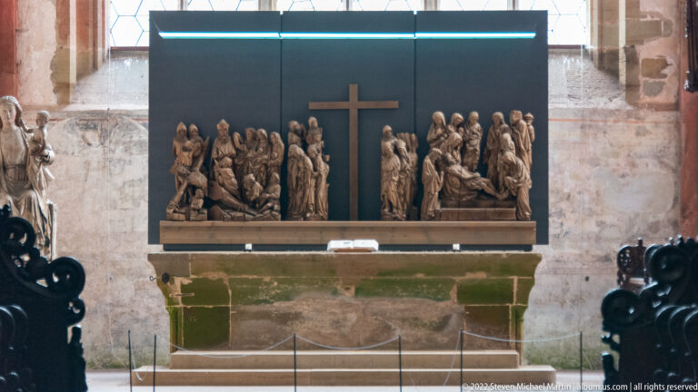 Carved religious figures grouped around a central cross above a stone altar.